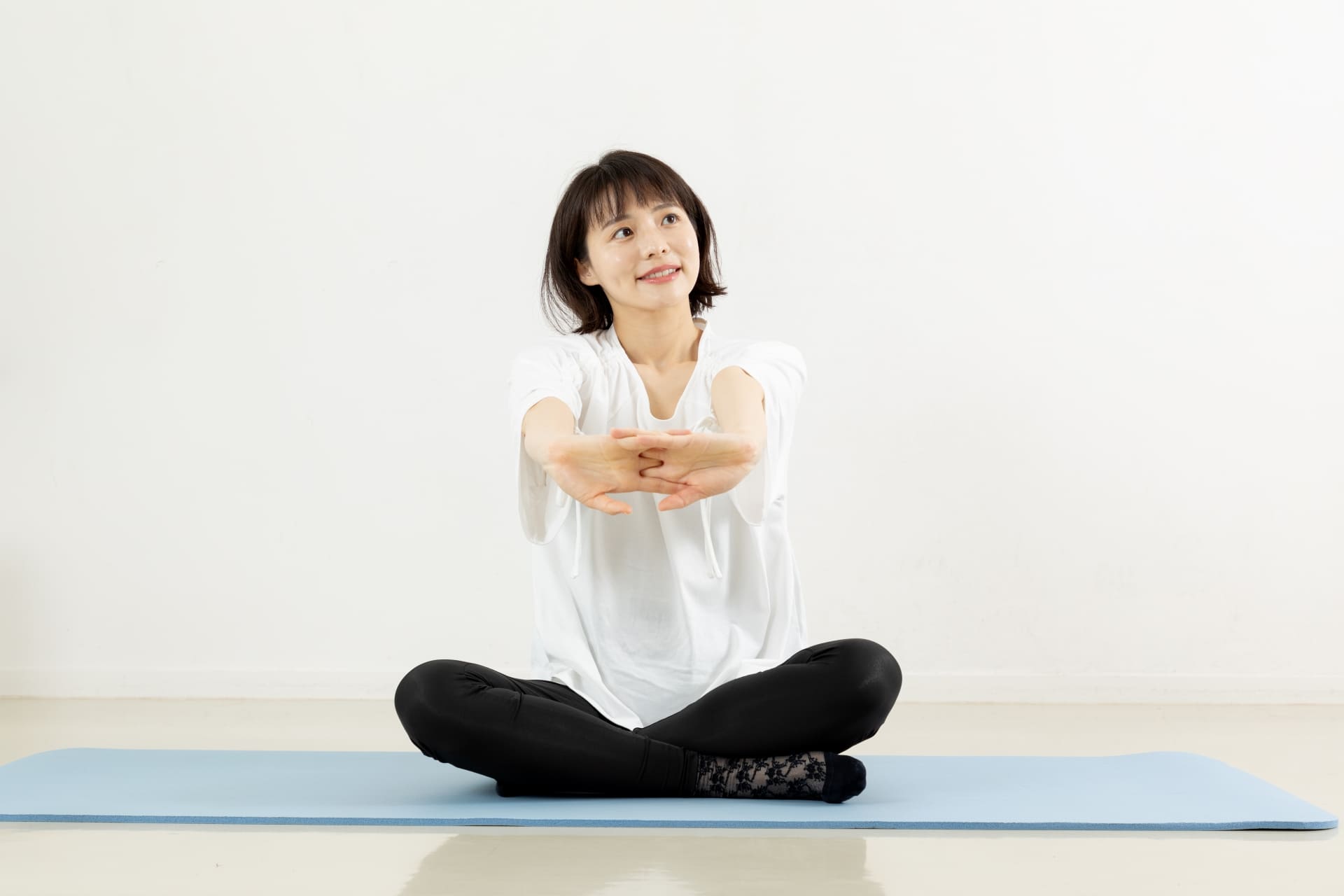 ヨガマットの上で体育座りをしてストレッチをする女性