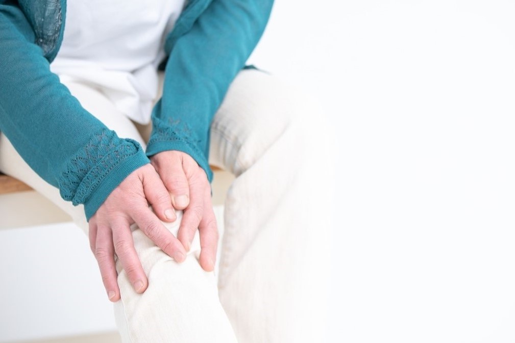 ひざに手を当てている様子で青緑色の長袖を着た人の手元