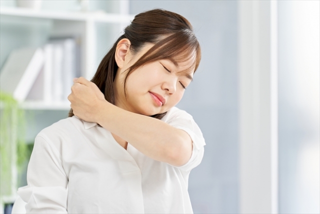 肩をさすっている女性